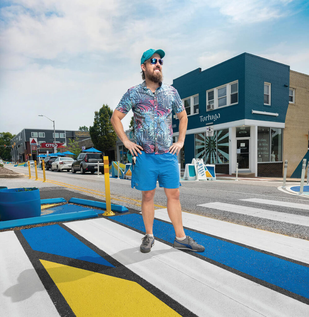 Public Artist Graham Coreil-Allen standing in a crosswalk surrounded by pavement art