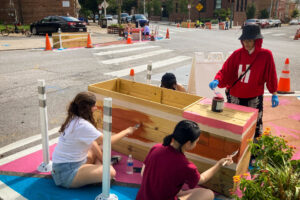 Pigtown Iconic Washington & Cross Community Paint Day volunteers painting wood planters.