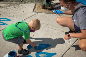 Pigtown Iconic Washington & Cross Community Paint Day child painting sidewalk.