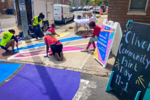 Oliver Allover Eyes community paint day a-frame signs and families painting on the sidewalk