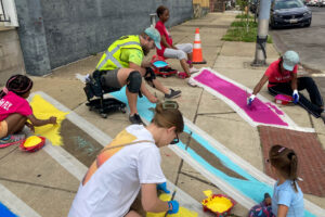 Oliver Allover Eyes community paint day Graham and youth painting the sidewalk