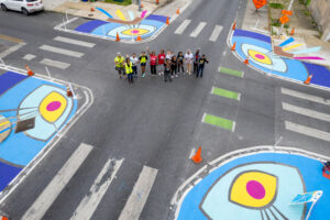Oliver Allover Eyes community paint day drone birds eye view of participants standing in the intersection