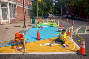 Reverberations Crosswalk volunteers painting reverberation lines on pavement