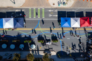 Damascus Placemaking Festival aerial view of pedestrians walking along curvilinear wayfinding pavement art and protect bike lane buffered by colorful vendor tents