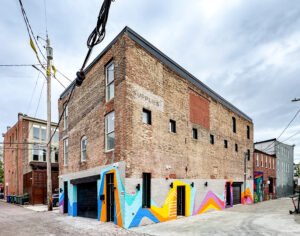 Exterior shot of the renovated 101 E Trenton with a colorful mural wrapping around the base of the building